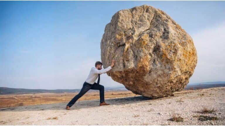 Person pushing large boulder representing productivity friction and resistance