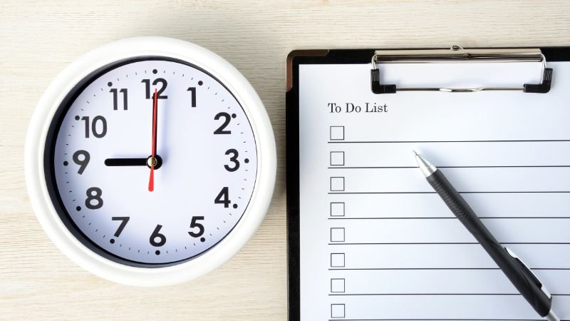 Picture of a long to-do list next to a clock, signifying poor task prioritisation and needing to use the 1-3-5 rule 