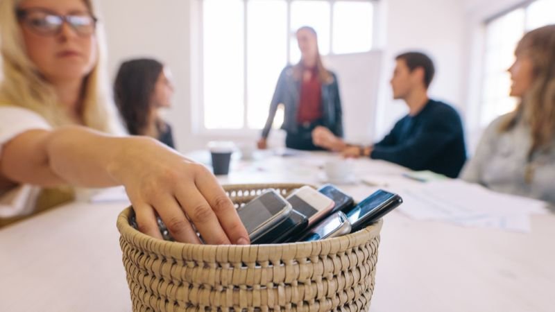 Professionals putting phones away during a meeting to minimise distractions